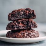 A stack of three delicious 10-Minuten Brownie-Cookies mit Kakao, showing their fudgy texture and melted chocolate.