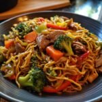 Close-up of Blitzschnelle Gebratene Nudeln mit Ente & Gemüse, featuring noodles, duck, broccoli, peppers, and carrots.