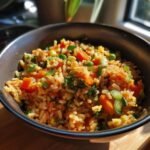 Close-up of Blitzschnelles Gebratener Reis mit Gemüse in a bowl, featuring rice, carrots, peas, and green onions.