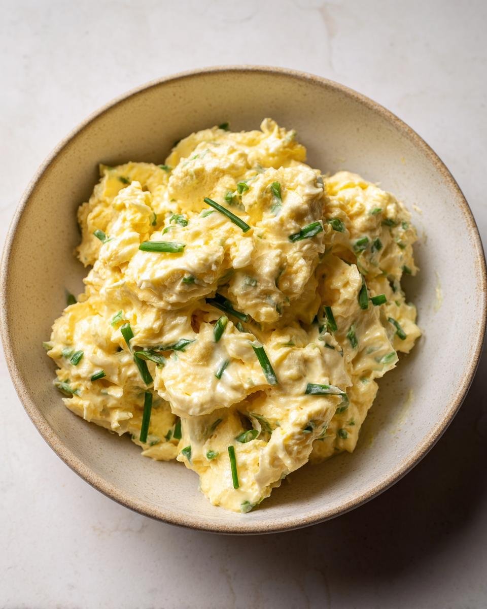 Bowl of Cremiger Eiersalat mit Schnittlauch & Senfcreme, a creamy German egg salad with chives and mustard.