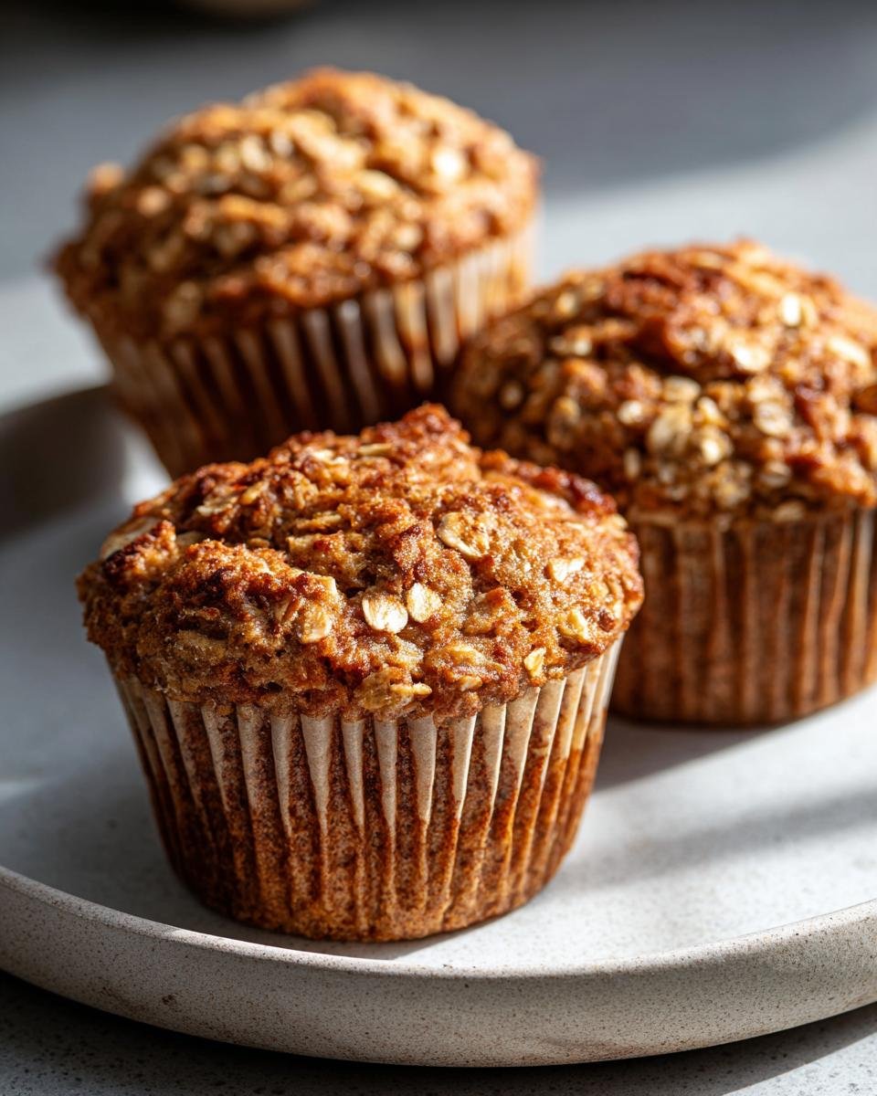 Three Gesunde Bananen-Hafer-Muffins on a plate, showcasing their texture and golden-brown color.