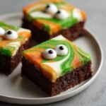 Close-up of Halloween Brownies with orange, green, and white frosting and candy eyes.