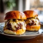 Two delicious Halloween Kürbis-förmige Sliders with melted cheese on a plate.