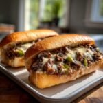 Two Keto Philly Cheesesteak Brötchen on a tray, filled with meat, mushrooms, peppers, and melted cheese.