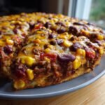 A slice of Krustenloser Taco-Kuchen, a crustless taco cake with beef, beans, corn, and melted cheese.