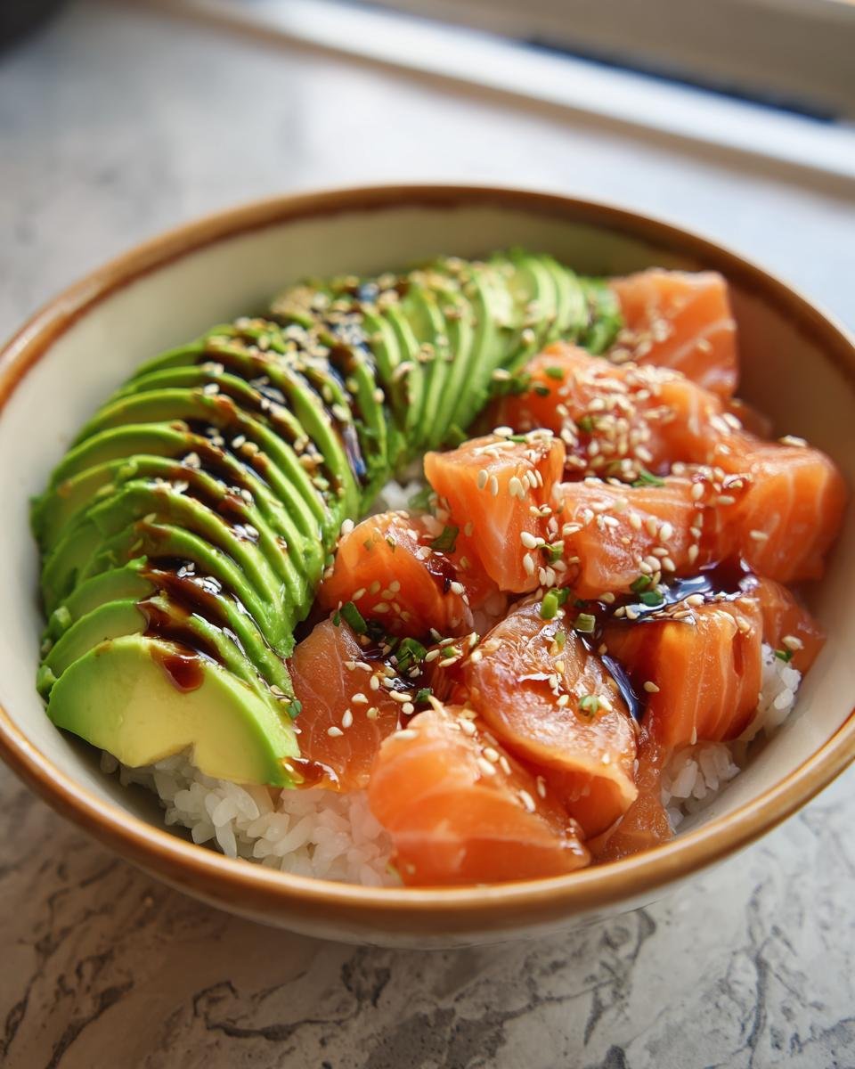 Close-up of a Lachs-Avocado-Bowl mit Sesam, showcasing fresh salmon, avocado slices, and sesame seeds on rice.