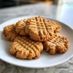 A stack of freshly baked Low Carb Erdnussbutterkekse (peanut butter cookies) on a white plate.