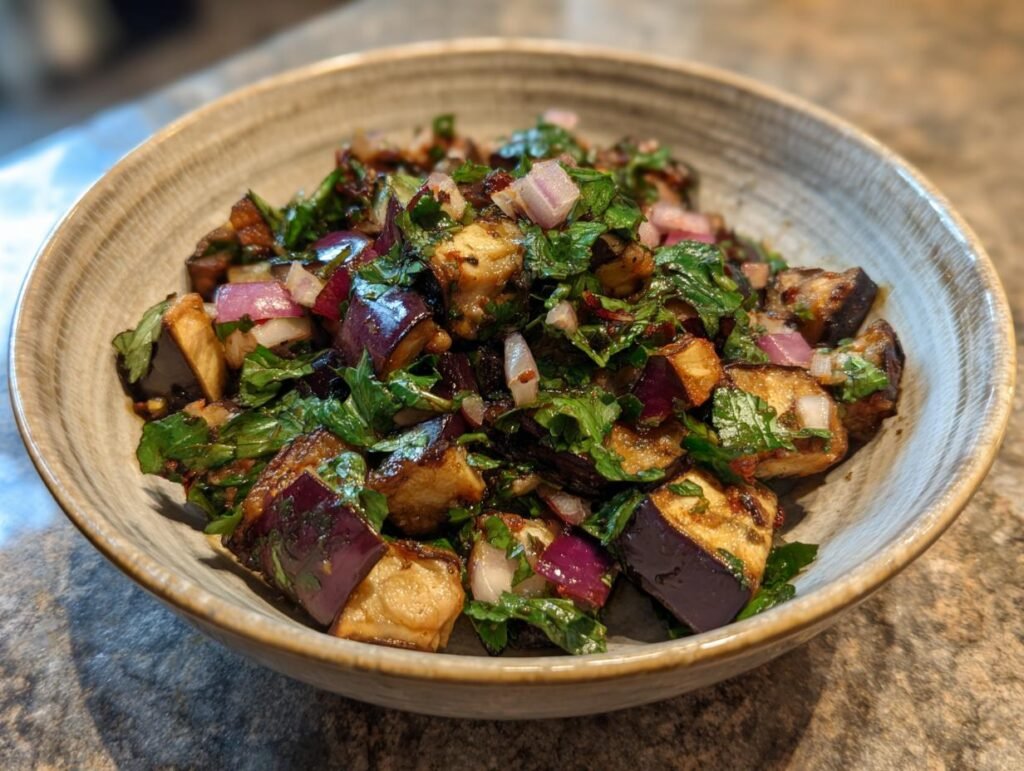 Mediterraner Auberginen-Salat mit Petersilie in einer Schüssel, mit Aubergine, Zwiebeln und Kräutern.