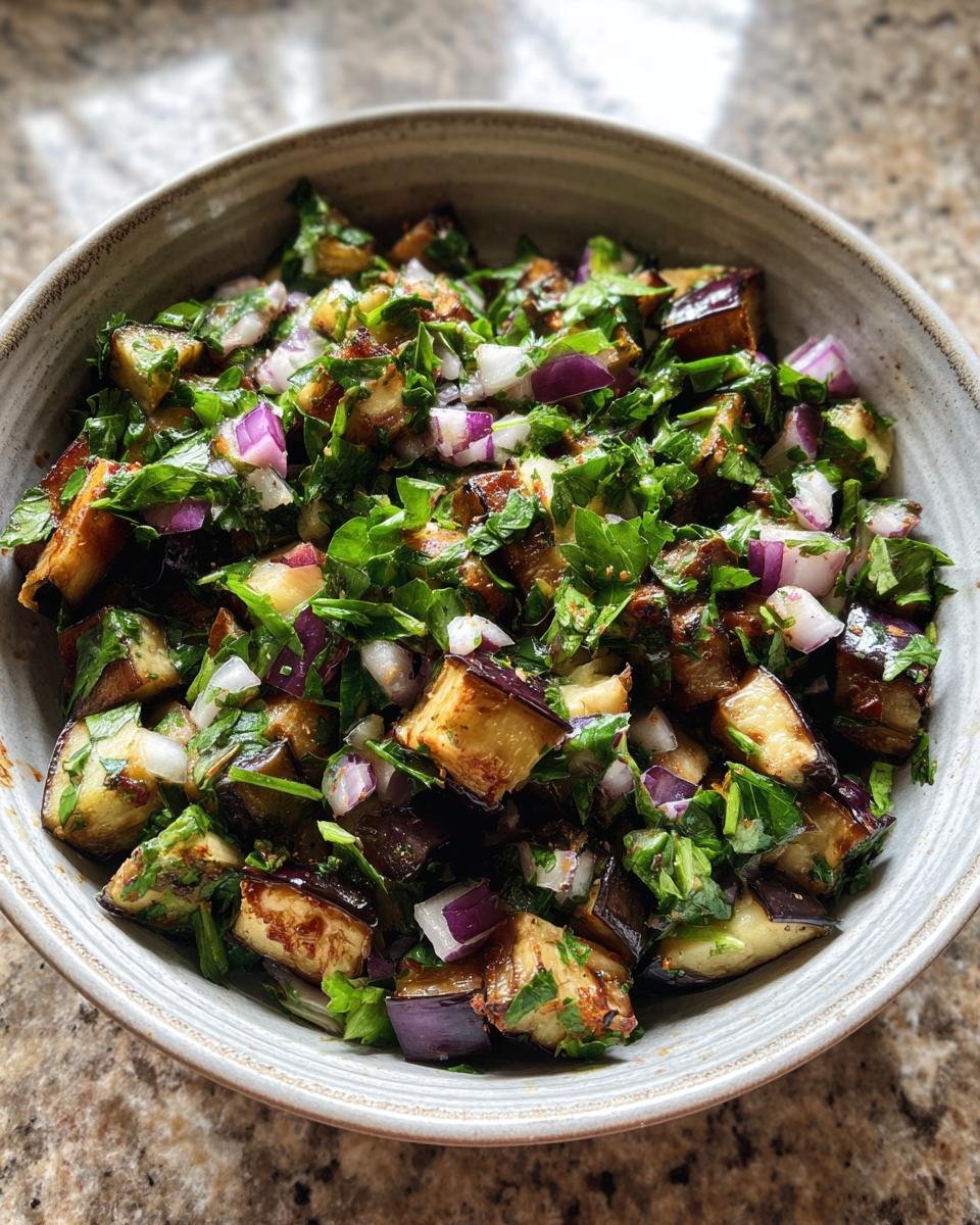 Close-up of Mediterraner Auberginen-Salat mit Petersilie, featuring eggplant, red onion, and parsley.