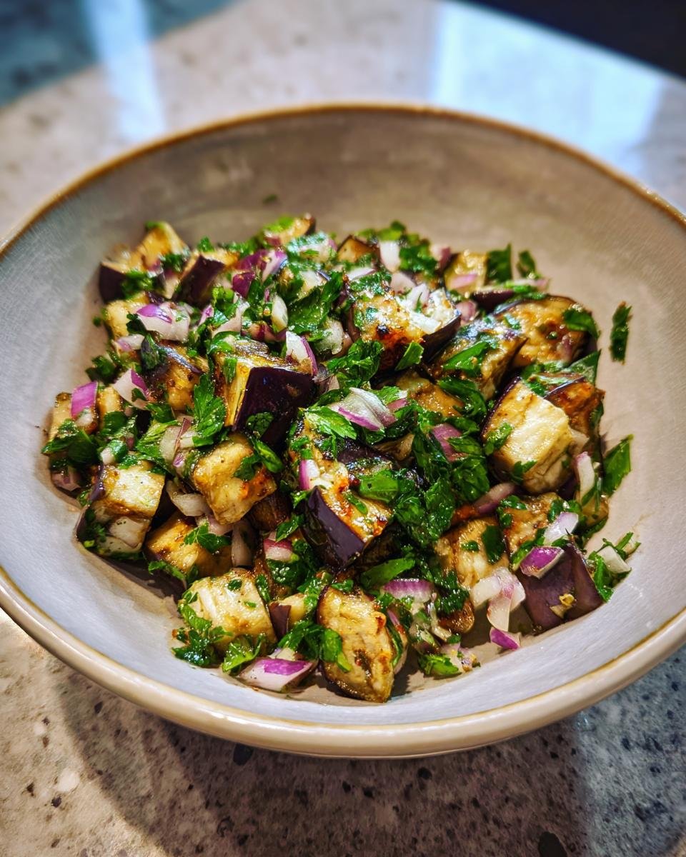 Mediterraner Auberginen-Salat mit Petersilie in einer Schüssel, mit Aubergine, Zwiebeln und Petersilie.