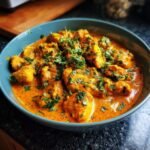 Nahaufnahme von Butter Chicken, garniert mit frischer Petersilie, ein köstliches Gericht.