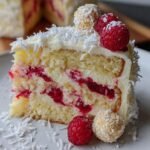 A slice of Himbeer-Raffaello-Torte ohne Gelatine, topped with raspberries and Raffaello candies.