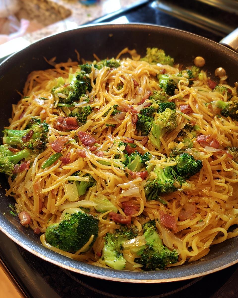 A pan filled with OnePan Brokkoli Schupfnudeln, featuring noodles, broccoli, and bacon.