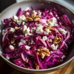 Close-up of a vibrant Rotkohl Feta Salat in a bowl, garnished with walnuts.
