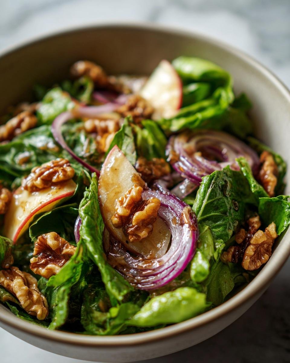 Close-up of Salat mit Apfel und karamellisierten Walnüssen in a bowl, featuring lettuce, apple slices, red onion, and walnuts.