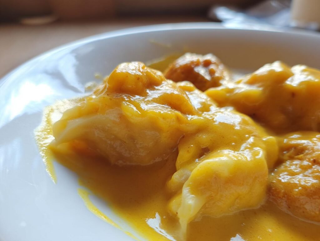Close-up of Vegane Linsenknödel in Curry Sauce, showing the texture and rich color of the dish.