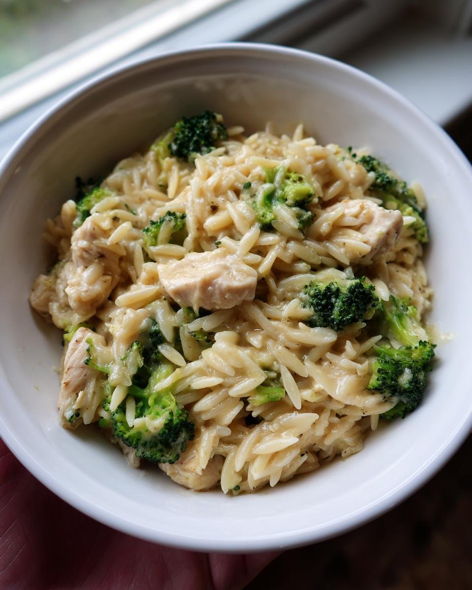 Nahaufnahme von Cremige Hähnchen-Brokkoli-Orzo mit Hähnchenstücken und Brokkoliröschen in einer cremigen Soße.