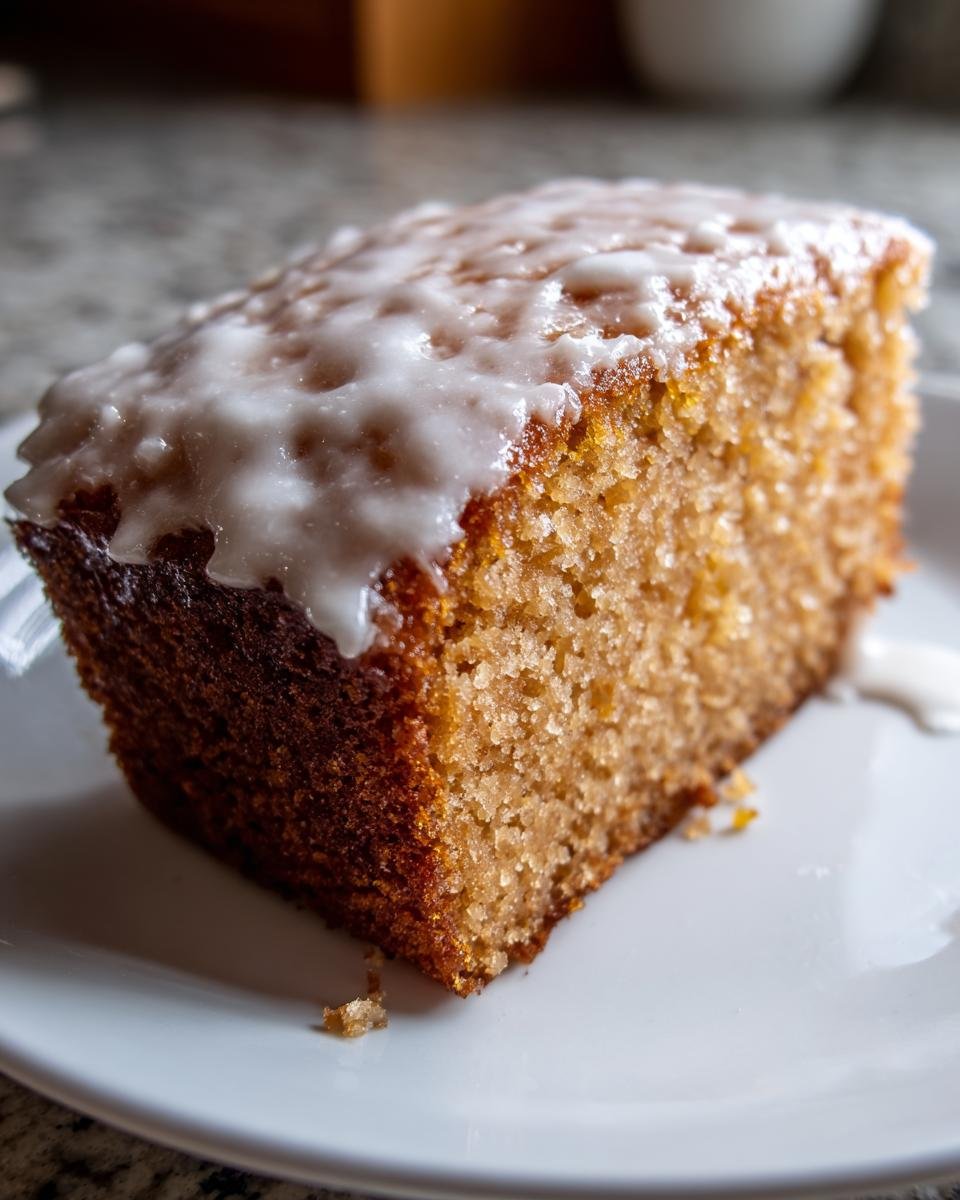 Nahaufnahme eines saftigen Stücks Fantakuchen vom Blech mit einer dicken Schicht weißem Zuckerguss.