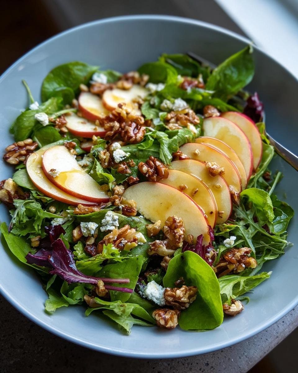 Nahaufnahme eines Apfel-Walnuss-Salat mit Blattsalat, belegt mit Apfelscheiben, Walnüssen und Blauschimmelkäse.